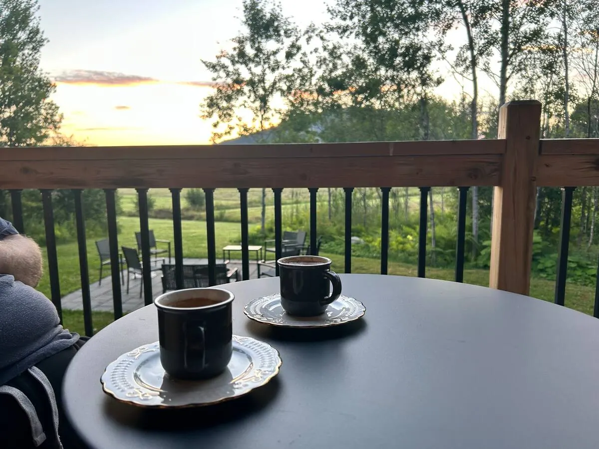 Two cups of coffee on a deck table at sunrise