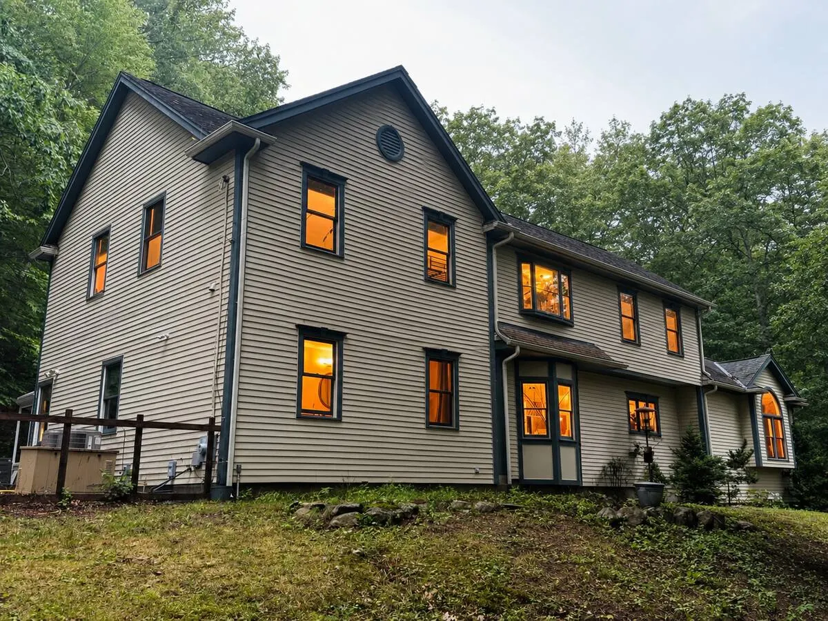 The exterior of a large Massachusetts home in daylight, framed by trees