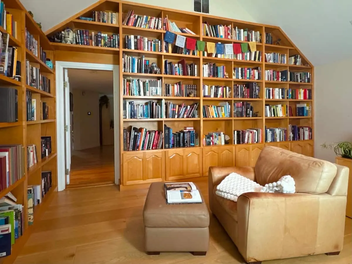 A custom-built library wall holding more than 1,000 books, with a leather sofa in front