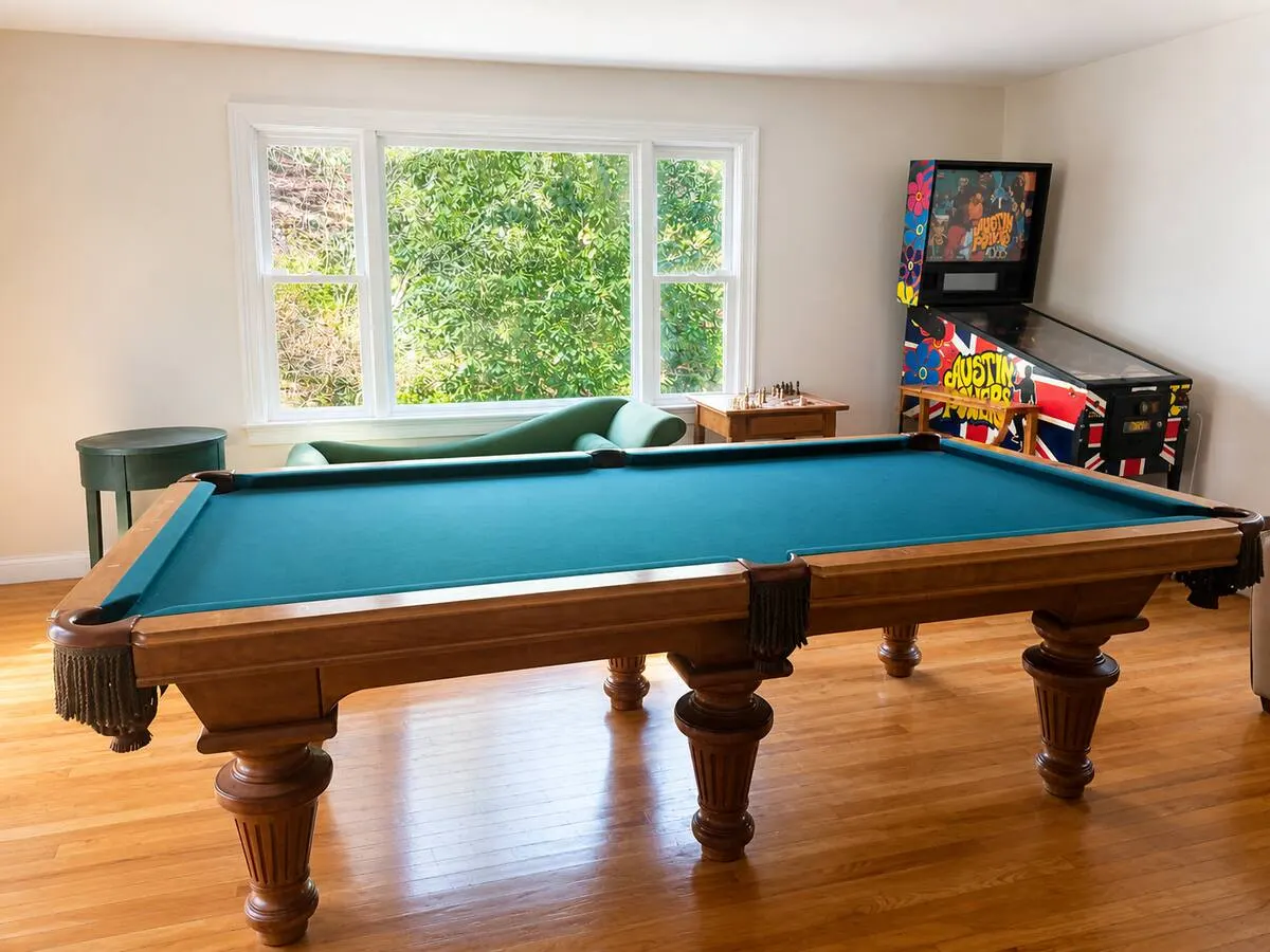 Pool table with green felt, a chess table by the window and a collector pinball machine in the Southborough game room